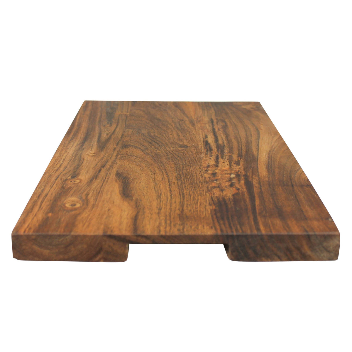 Low-angle view of an acacia cutting board showing the recessed finger grips