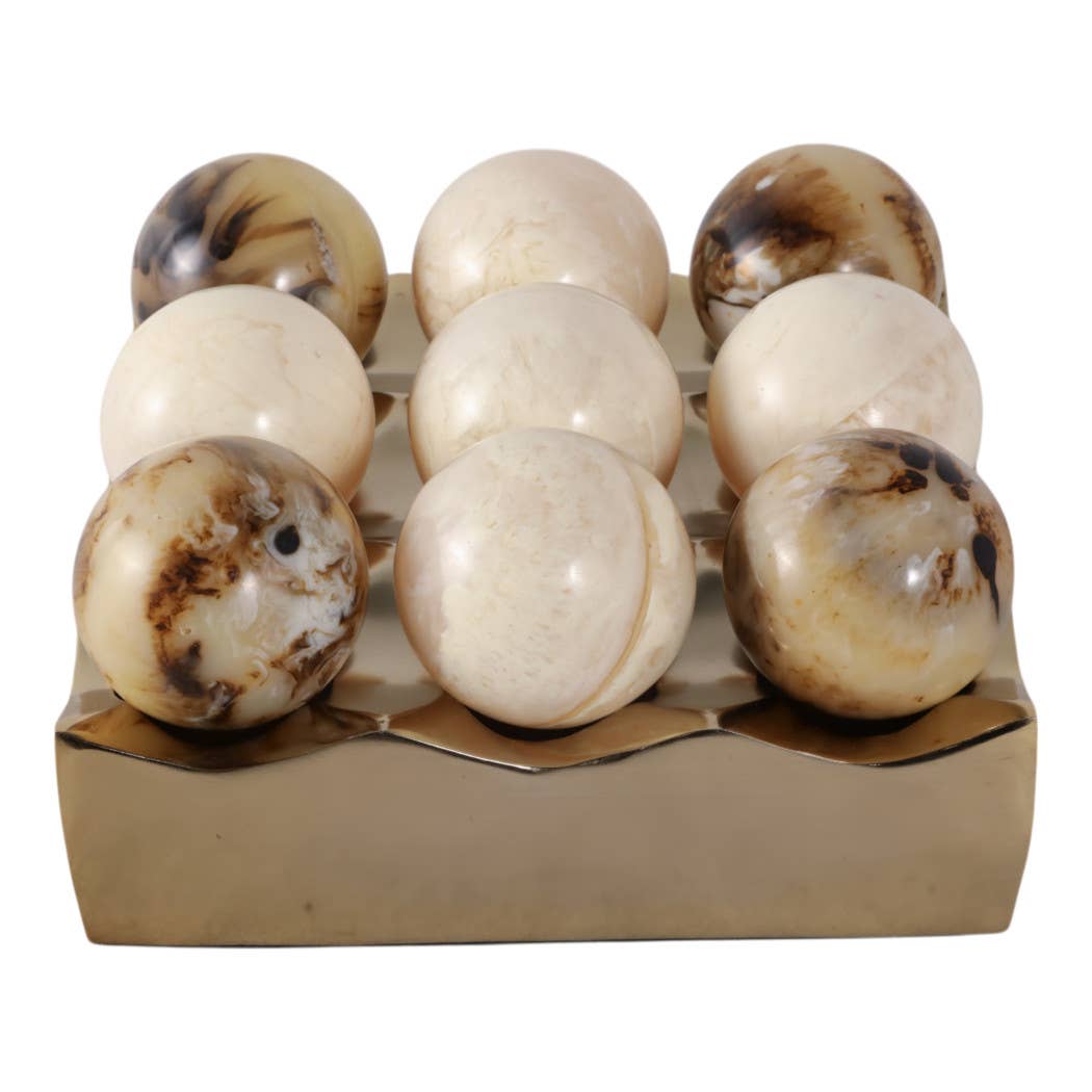 Close-up of cream and brown marble ball pieces sitting in the gold tic-tac-toe tray