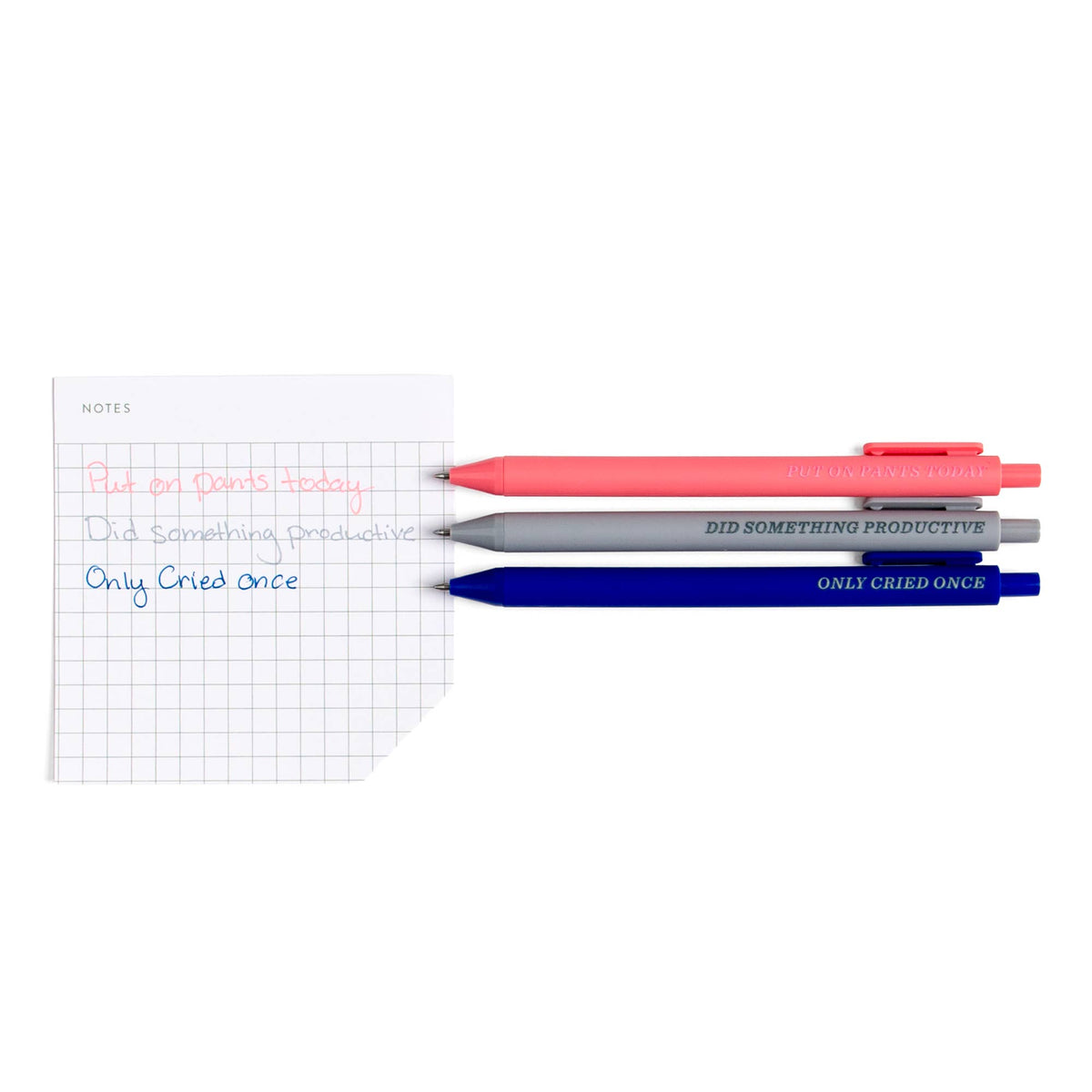 Little Victories gel pens beside a grid sticky note written in matching pink, gray and navy ink