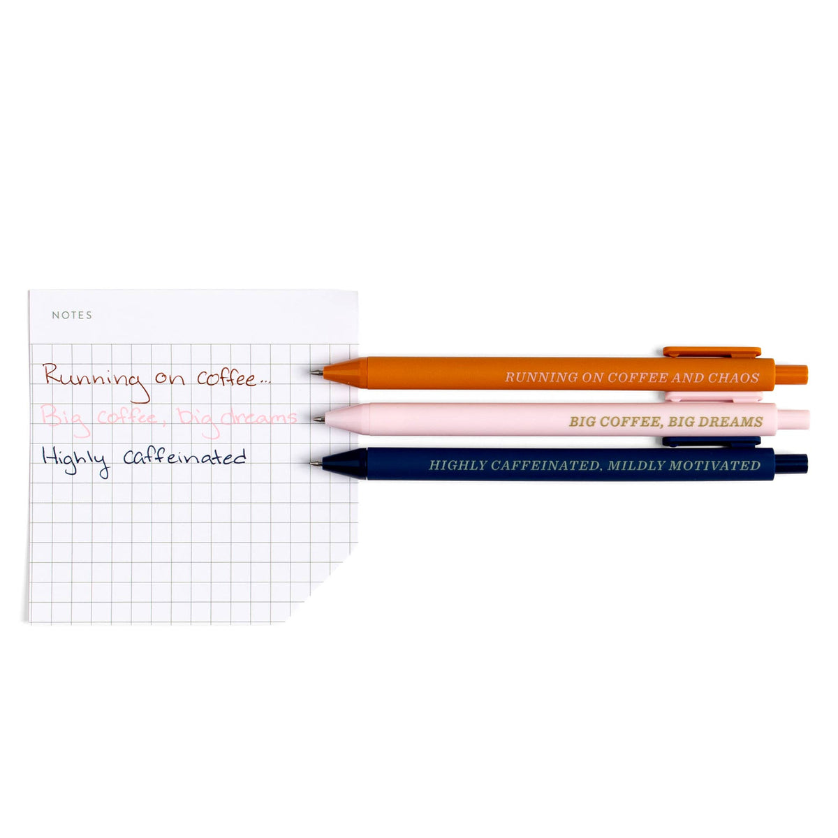 Highly Caffeinated gel pens beside a grid sticky note written in matching rust, pink and navy ink