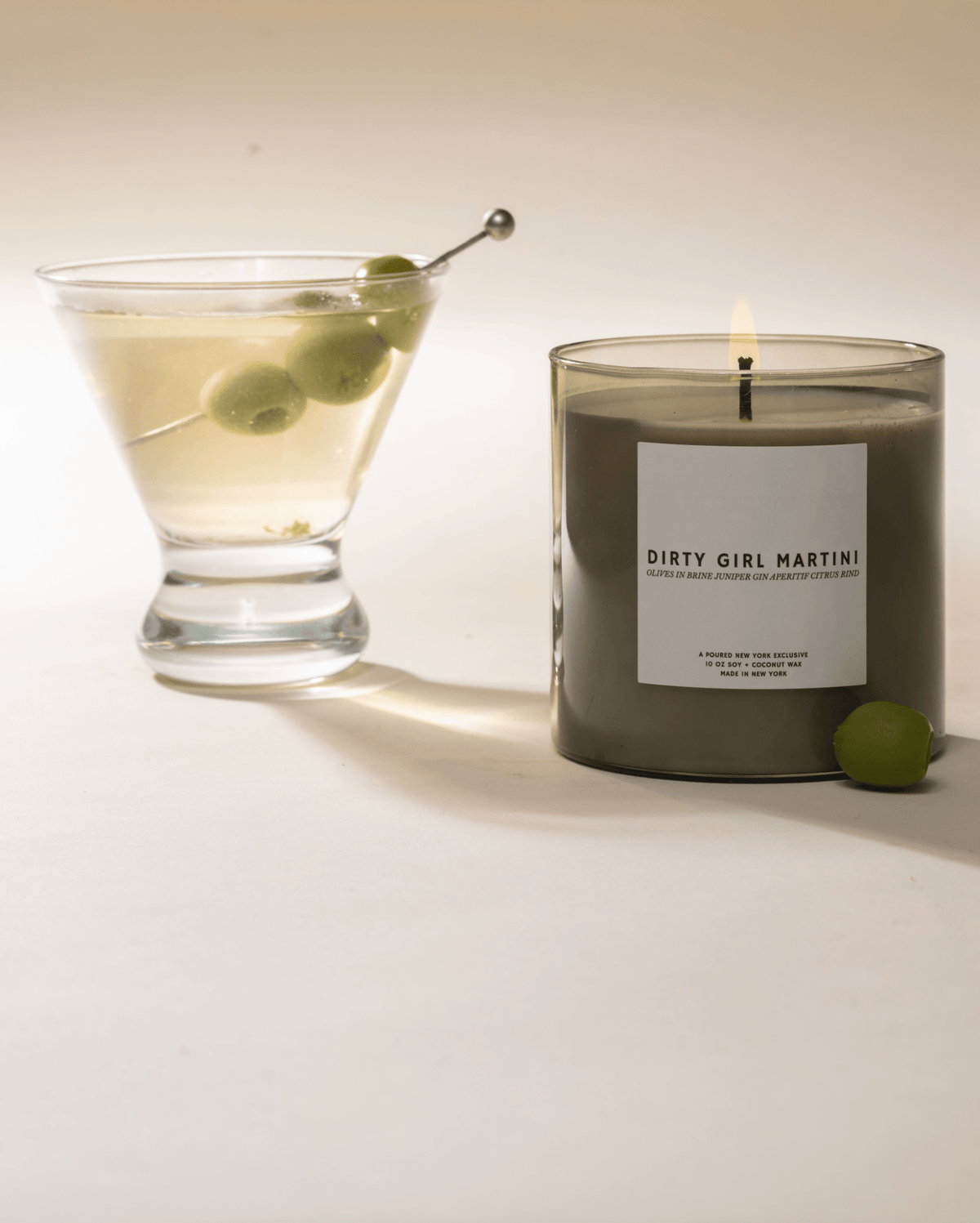 Dirty Girl Martini candle styled beside a martini glass with olives