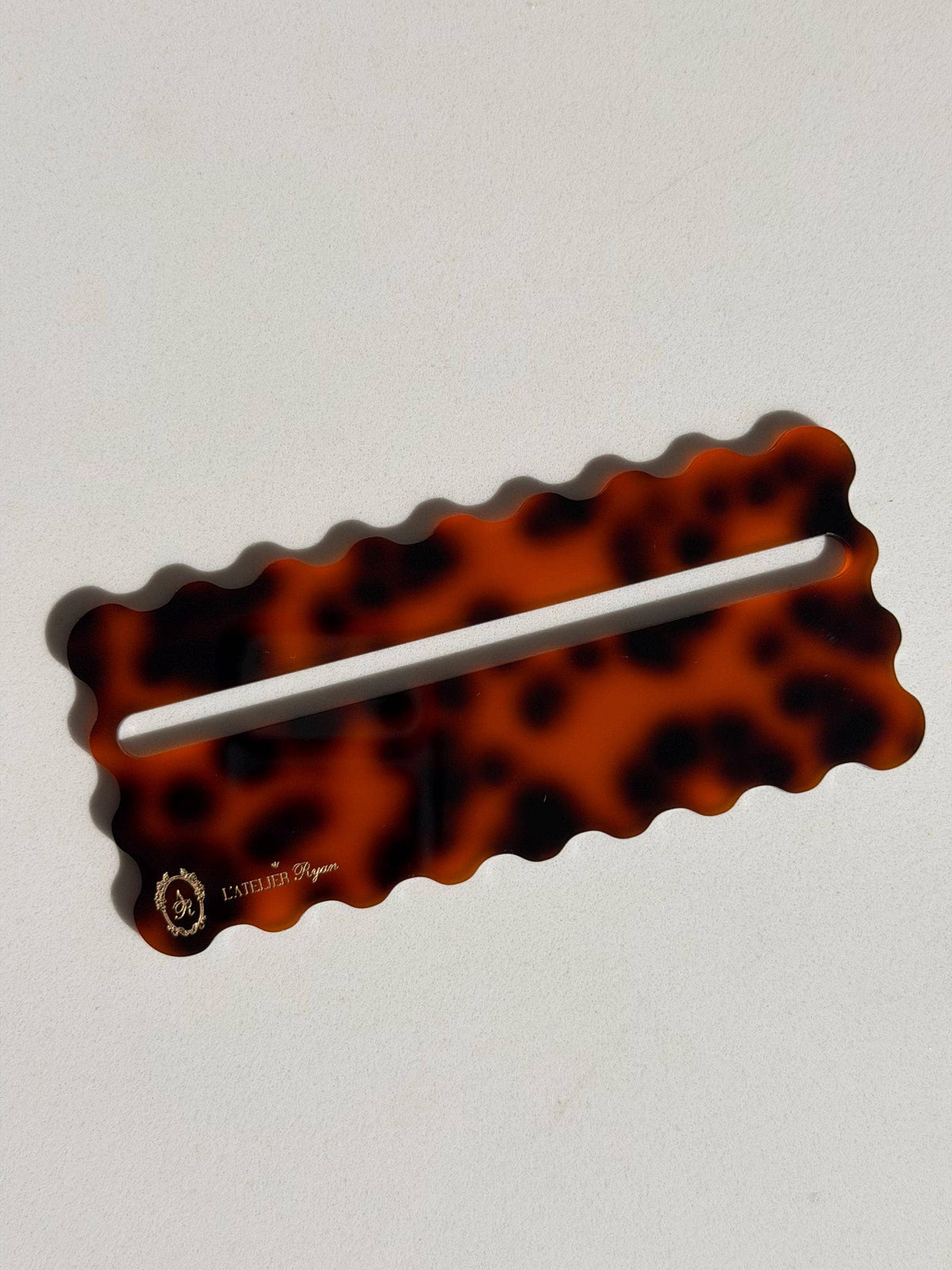 Tortoiseshell acrylic Mahjong line reader with scalloped edges on a plain background