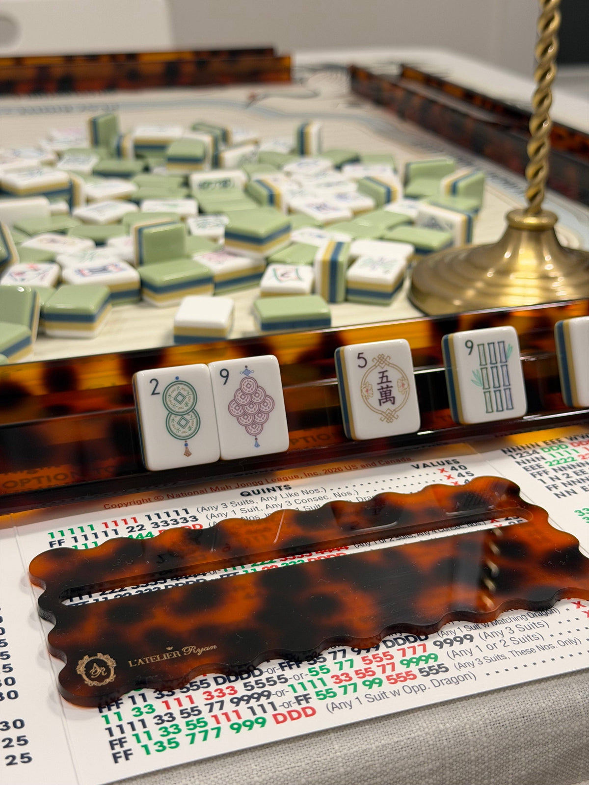 Tortoiseshell line reader on a Mahjong card at a game table with tiles on racks