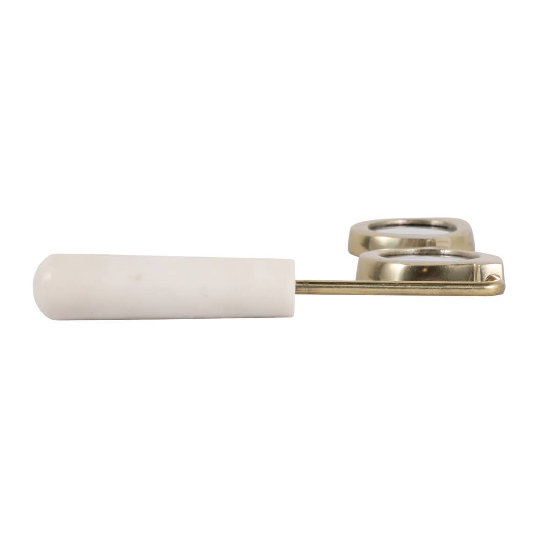 Gold and marble magnifying glass lying flat, handle side view