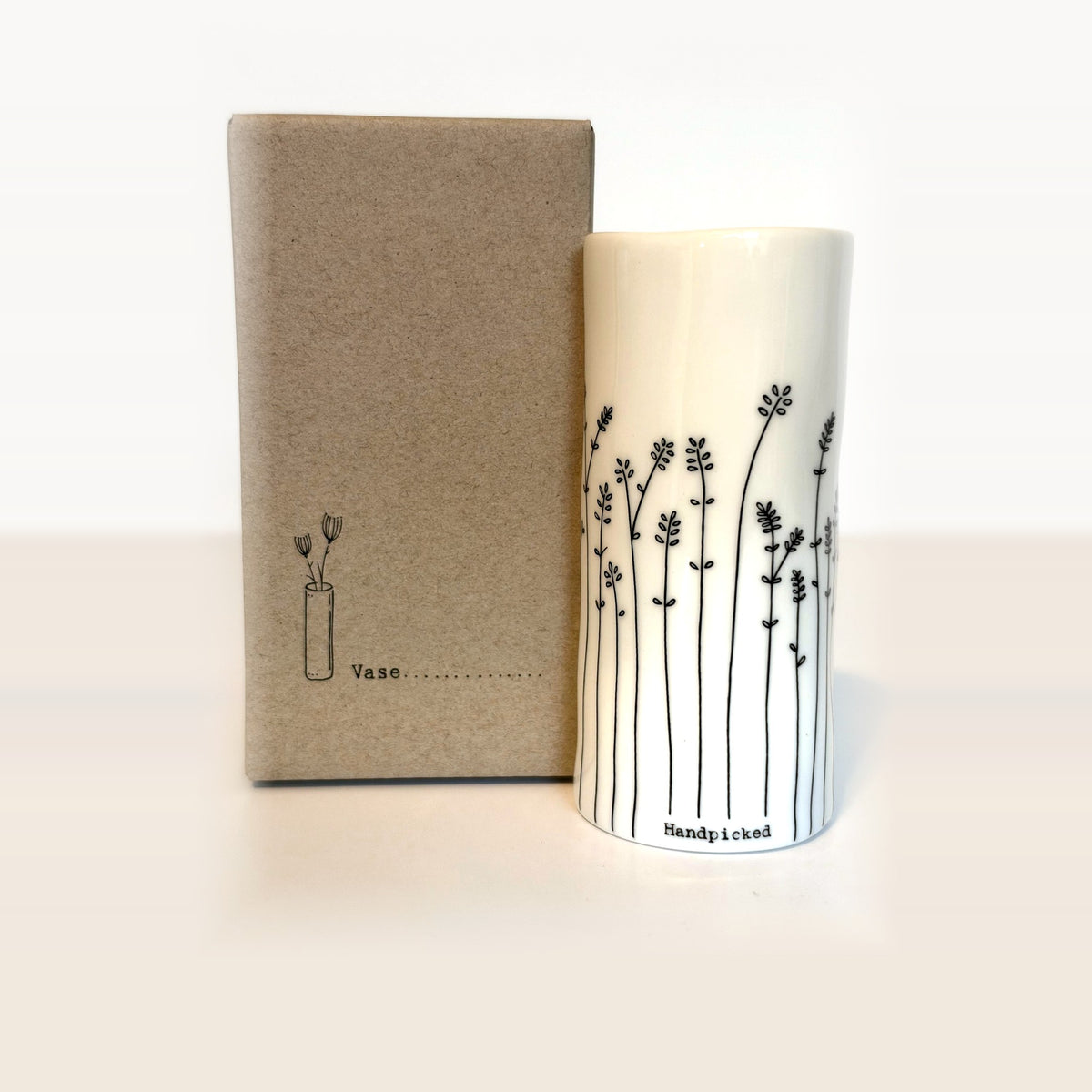 Handpicked mini porcelain vase with hand-drawn leafy sprigs next to its kraft gift box