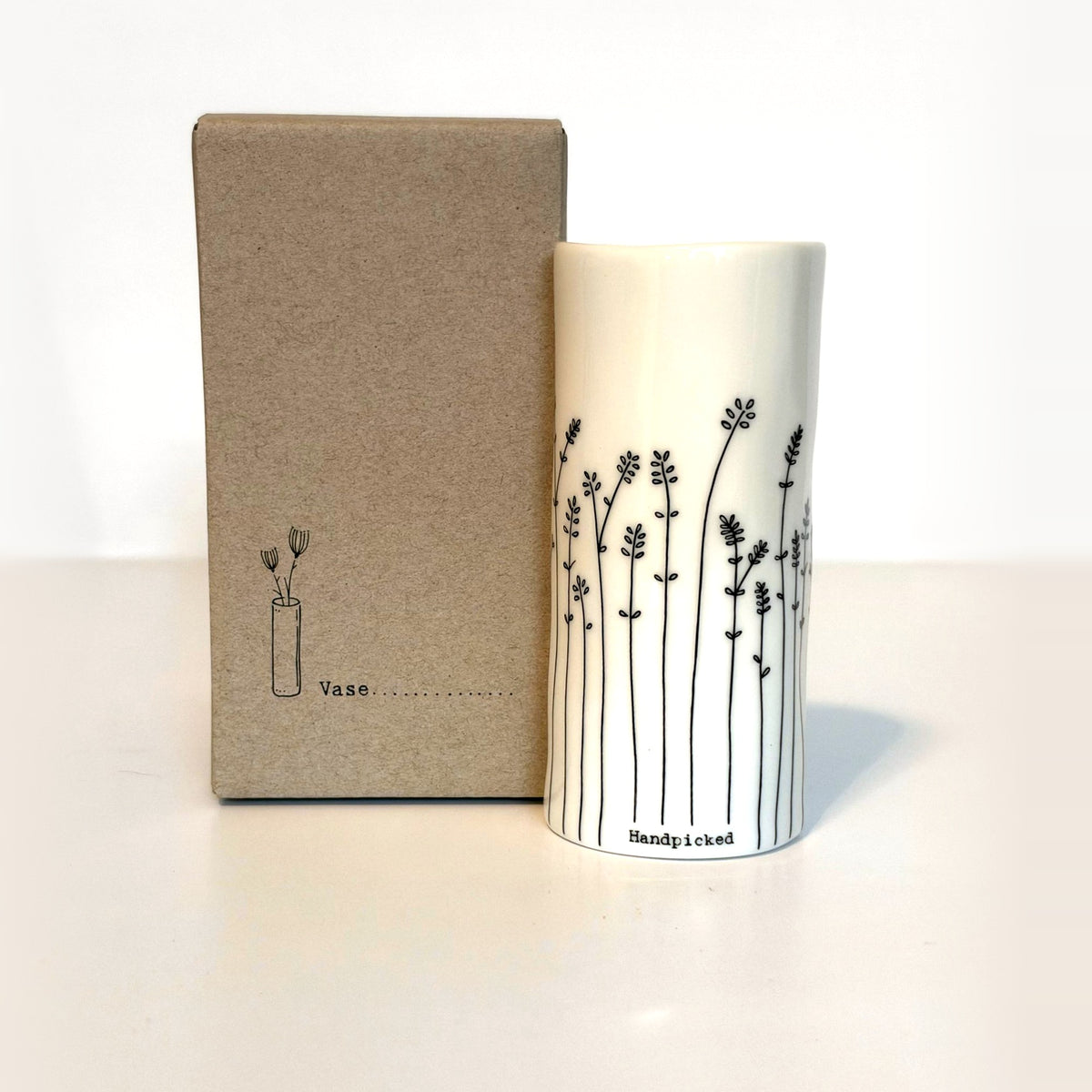 Handpicked mini porcelain vase with hand-drawn leafy sprigs next to its kraft gift box
