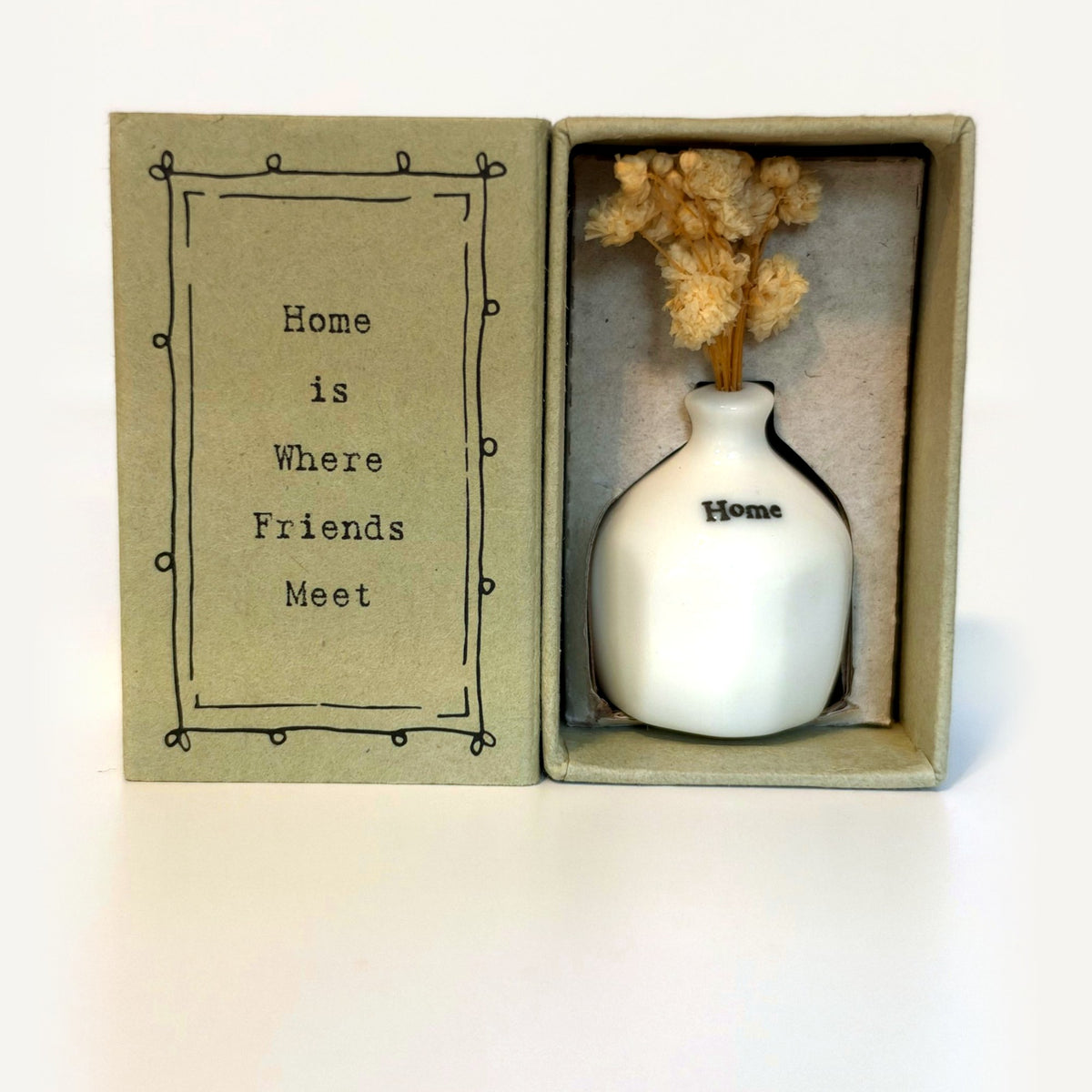 Home tiny vase gift box: white porcelain vase with cream dried flowers beside a card reading Home Is Where Friends Meet